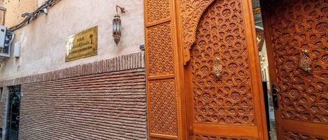 Fachada de edificio con una puerta de madera tradicional adornada con intrincados grabados y un letrero.