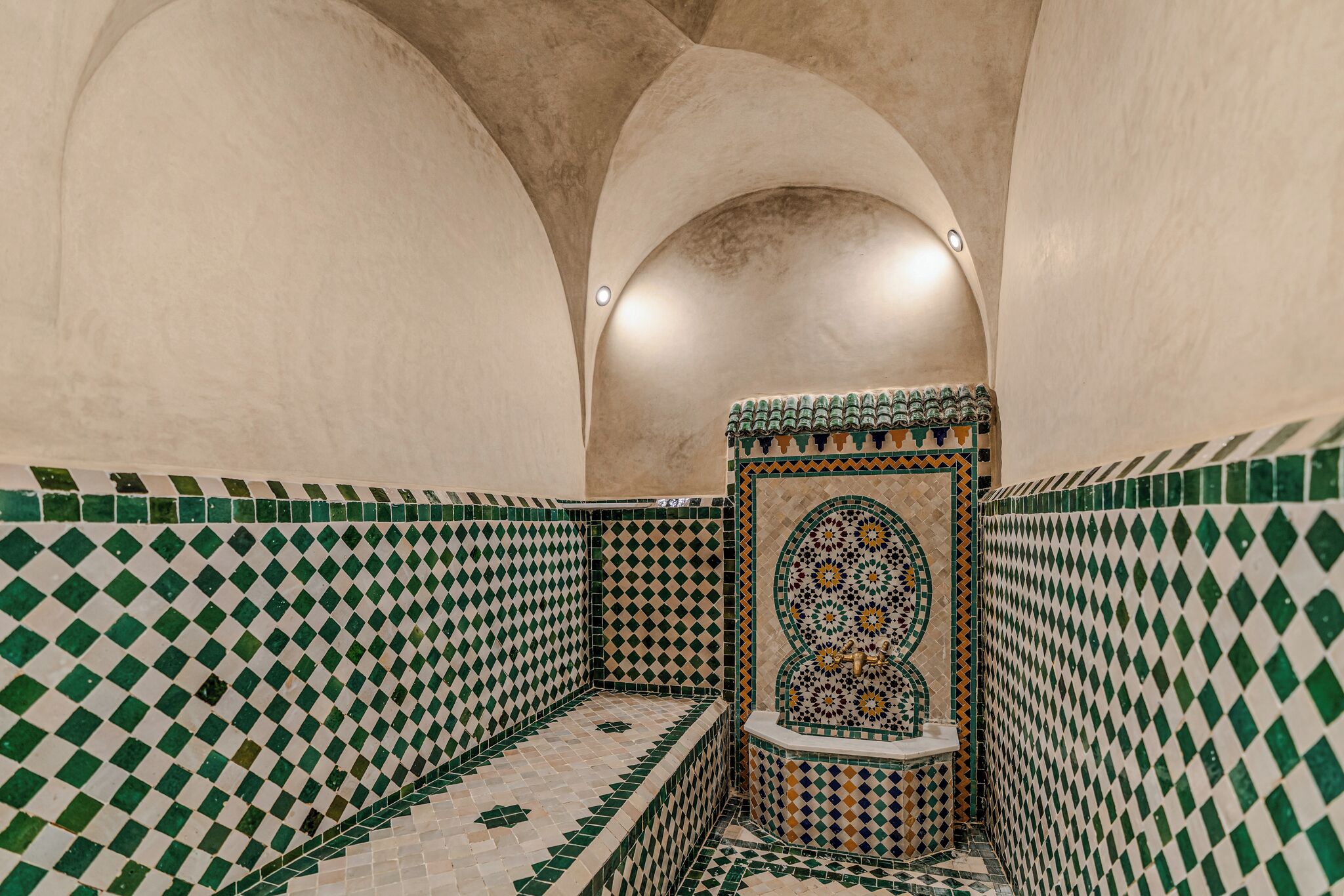 Un baño con baldosas de estampado a cuadros, un nicho decorativo y techo abovedado.