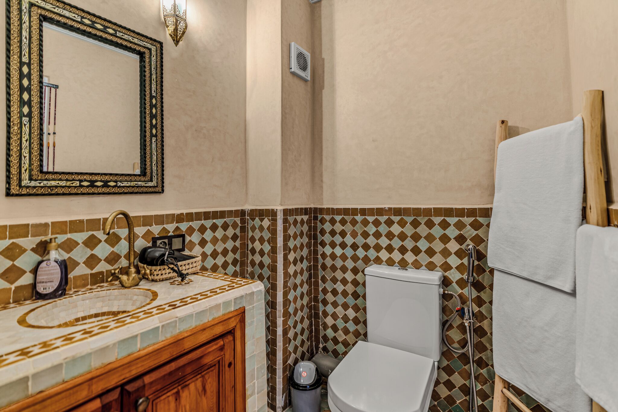 A bathroom with a sink, mirror, toilet, and shower area.