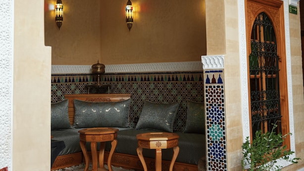 A cozy interior with a sofa, two small tables, and a decorative wall with intricate patterns. - Riad Maison D'HÔTE ABDEL & JAMILA (Marrakech)