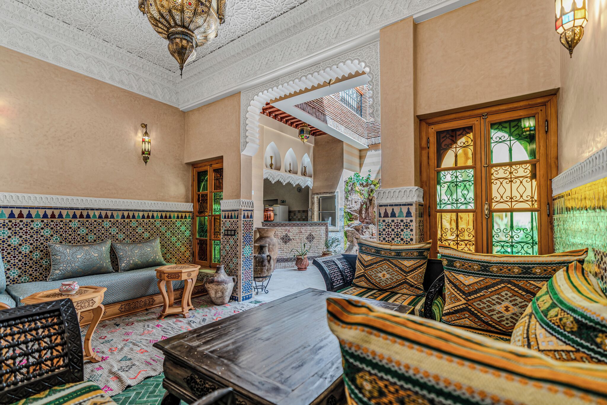 Un intérieur marocain traditionnel avec un canapé, des coussins à motifs, une table basse en bois et une lanterne décorative.