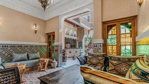 A traditional Moroccan interior with a sofa, patterned cushions, a wooden coffee table, and a decorative lantern. - Riad Maison D'HÔTE ABDEL & JAMILA (Marrakech)