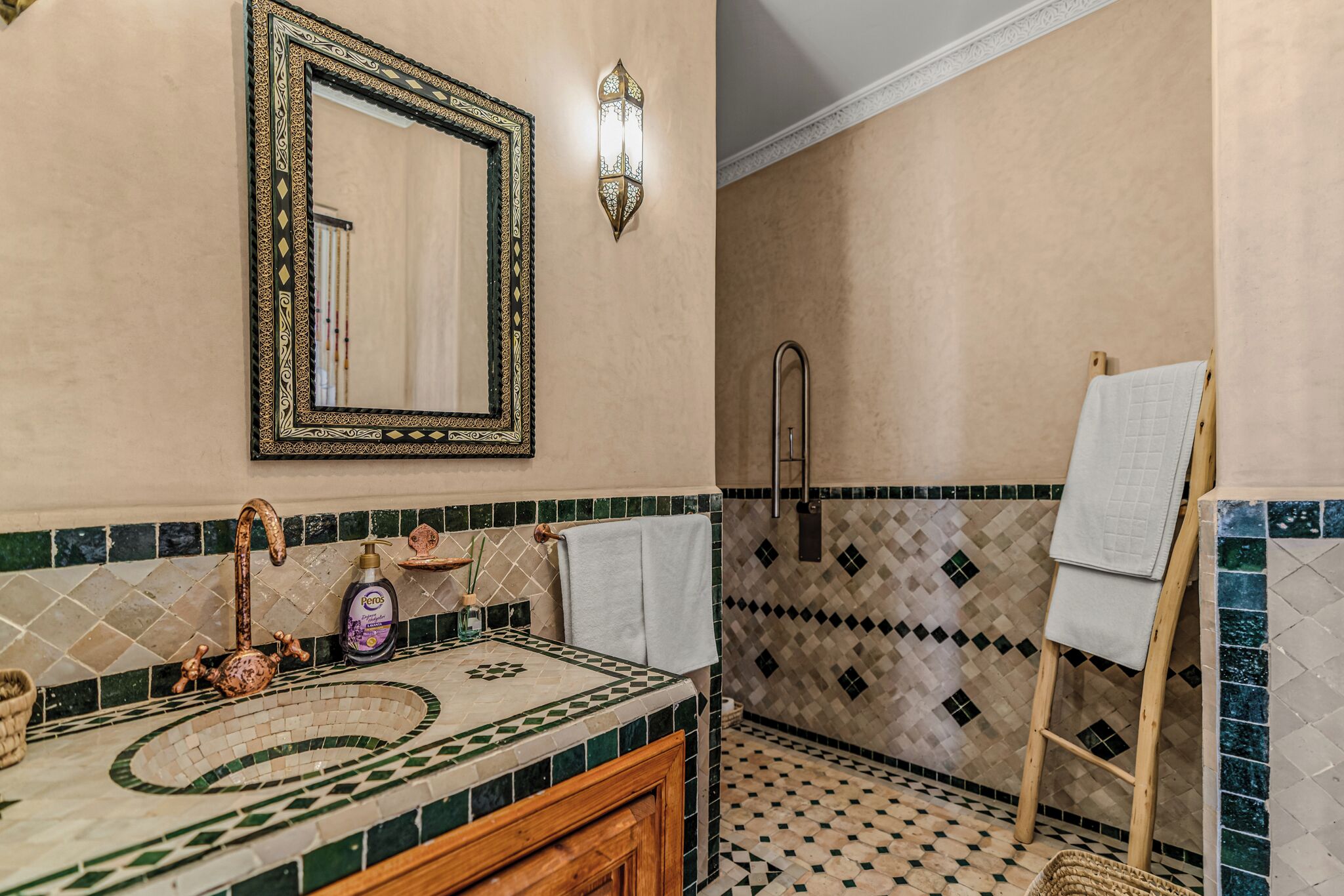 Een badkamer met een wastafel, spiegel en douchehoek.