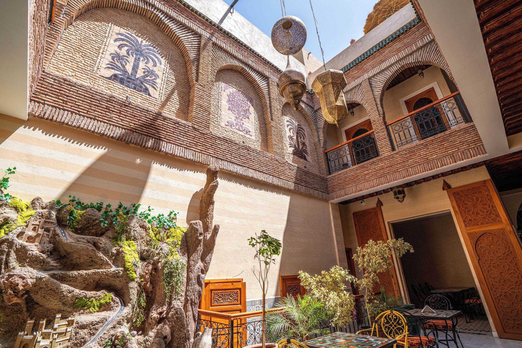 A courtyard with a fountain, seating area, and a view of a building with intricate tile work.