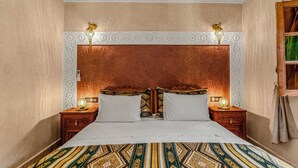 A bedroom with a large bed, two nightstands, a decorative headboard, and two wall-mounted lamps. - Riad Maison D'HÔTE ABDEL & JAMILA (Marrakech)