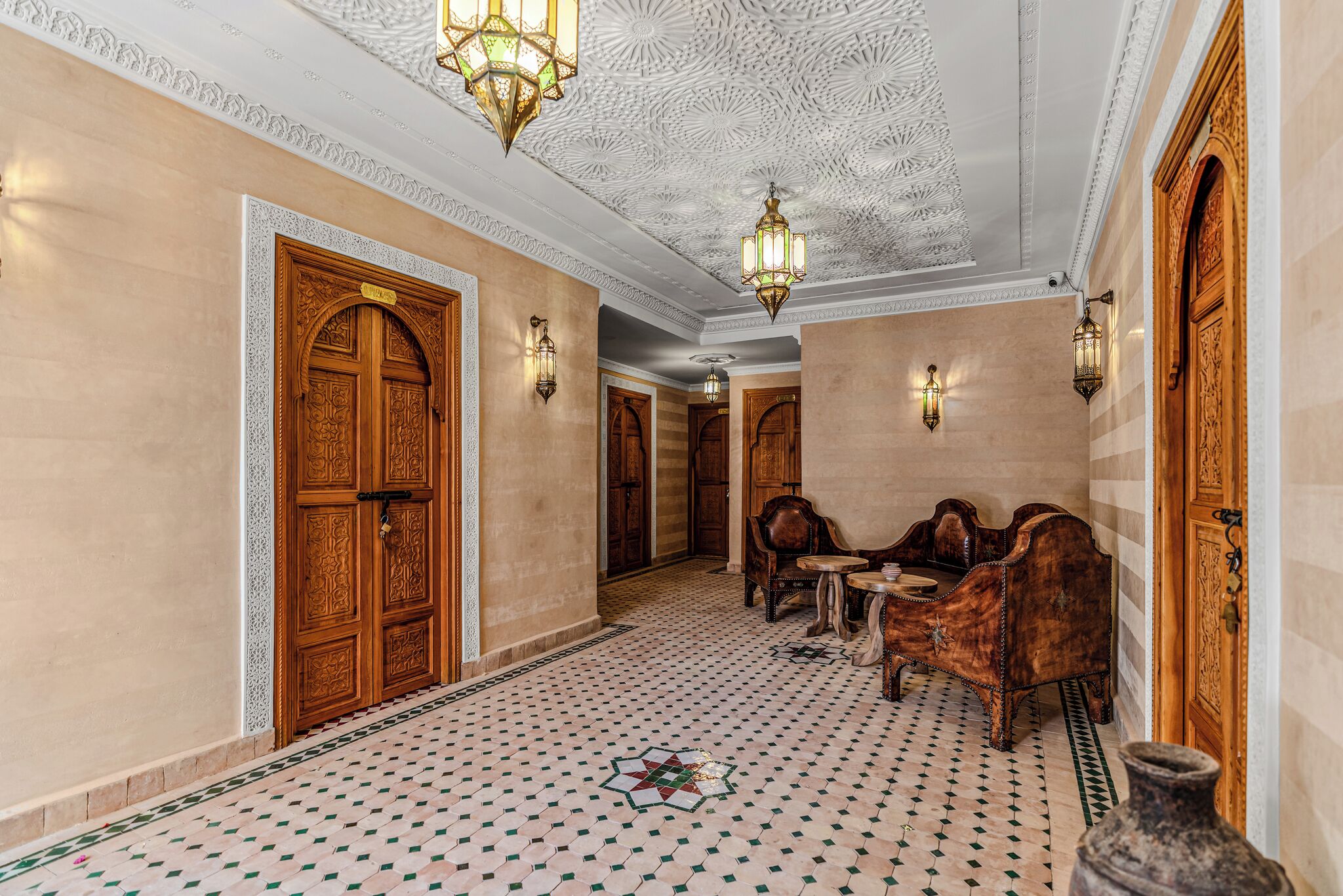Un couloir agrémenté de portes en bois sculptées, de carreaux de sol à motifs et de meubles de style traditionnel.
