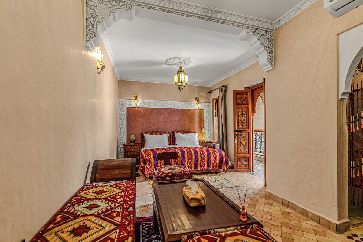 A traditional room with a bed, a coffee table, and a decorative wall.