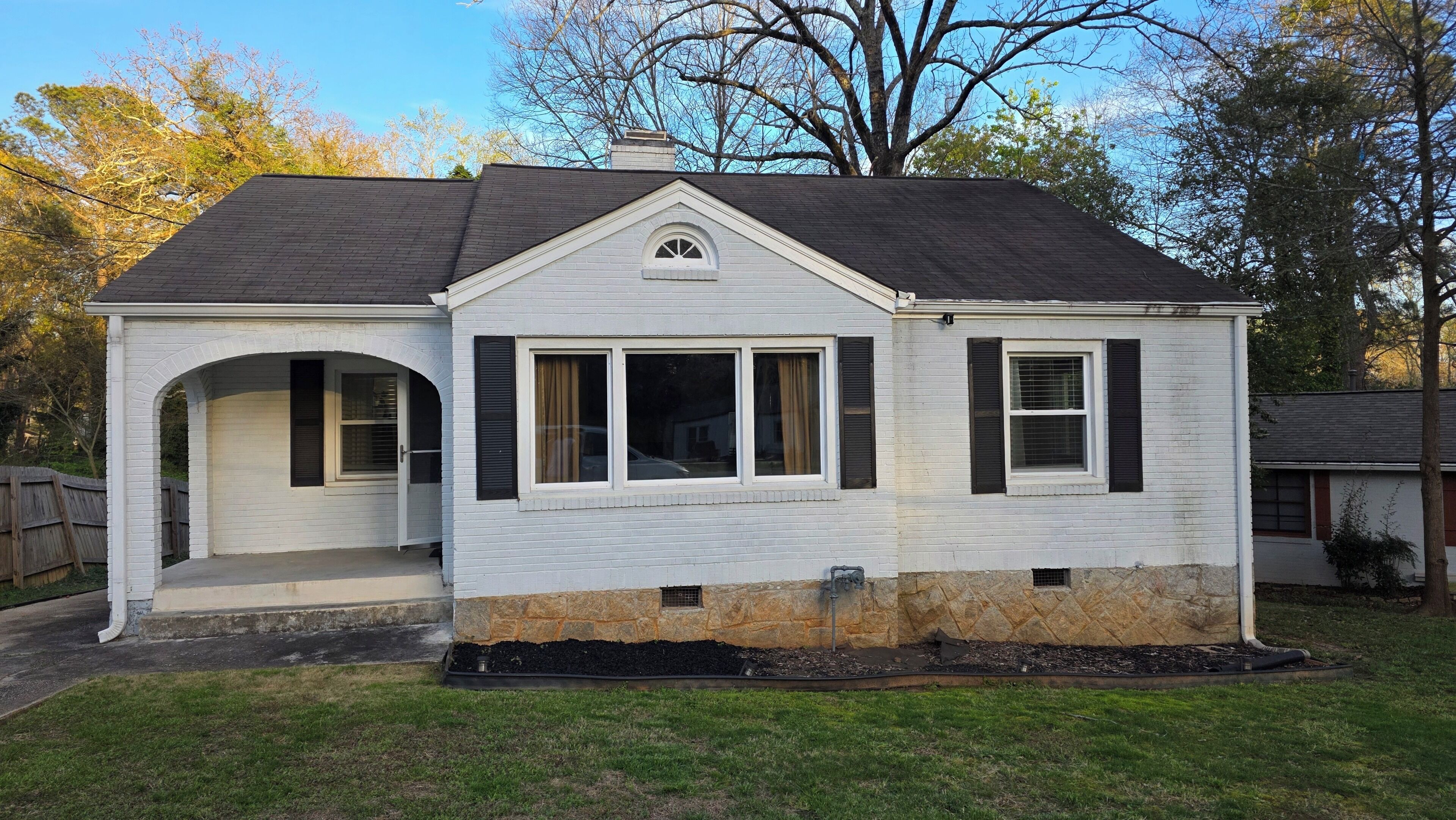 A single-story house with a gabled roof, a front porch, and a stone foundation.