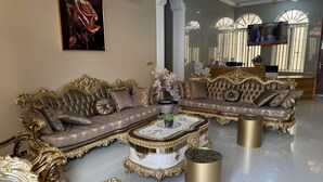 A luxurious living room with ornate sofas, a marble coffee table, and a television in the background. - Pera Imperial hotel (Iringa)