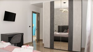 A modern hotel room with a bed, a desk, a chair, a flat-screen TV, and a large mirror. - Luca's House (Giovinazzo)