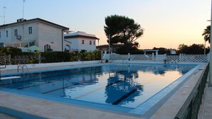 A rectangular swimming pool with a tiled edge, surrounded by a low wall and a white fence. - Luca's House (Giovinazzo)