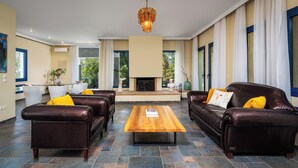 Amplia sala de estar con sofás de cuero, una mesa de centro de madera y una chimenea.