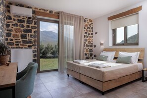 Un dormitorio con pared de piedra, una cama con almohadas, un escritorio y vistas al exterior.
