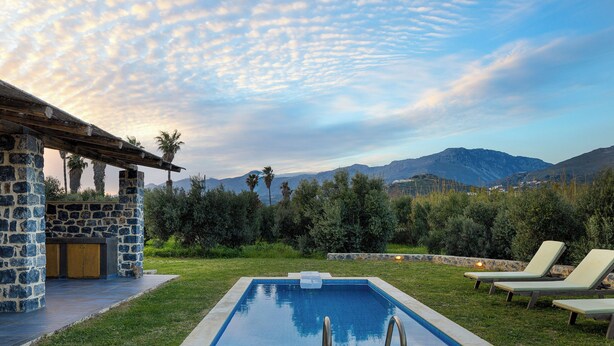 A swimming pool with lounge chairs, a stone structure, and a view of mountains.