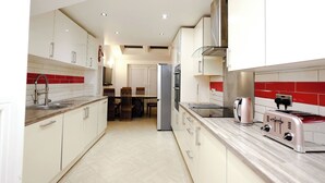 A modern kitchen with white cabinets, a stainless steel refrigerator, and a toaster. - Cozy Place in Salford, Sleeps 8, 4 Bedroom, 5 Beds (Salford)