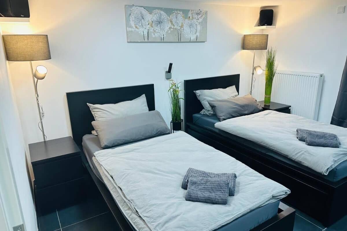 Een moderne slaapkamer met twee bedden, bedlampen, een kunstwerk aan de muur en een radiator.