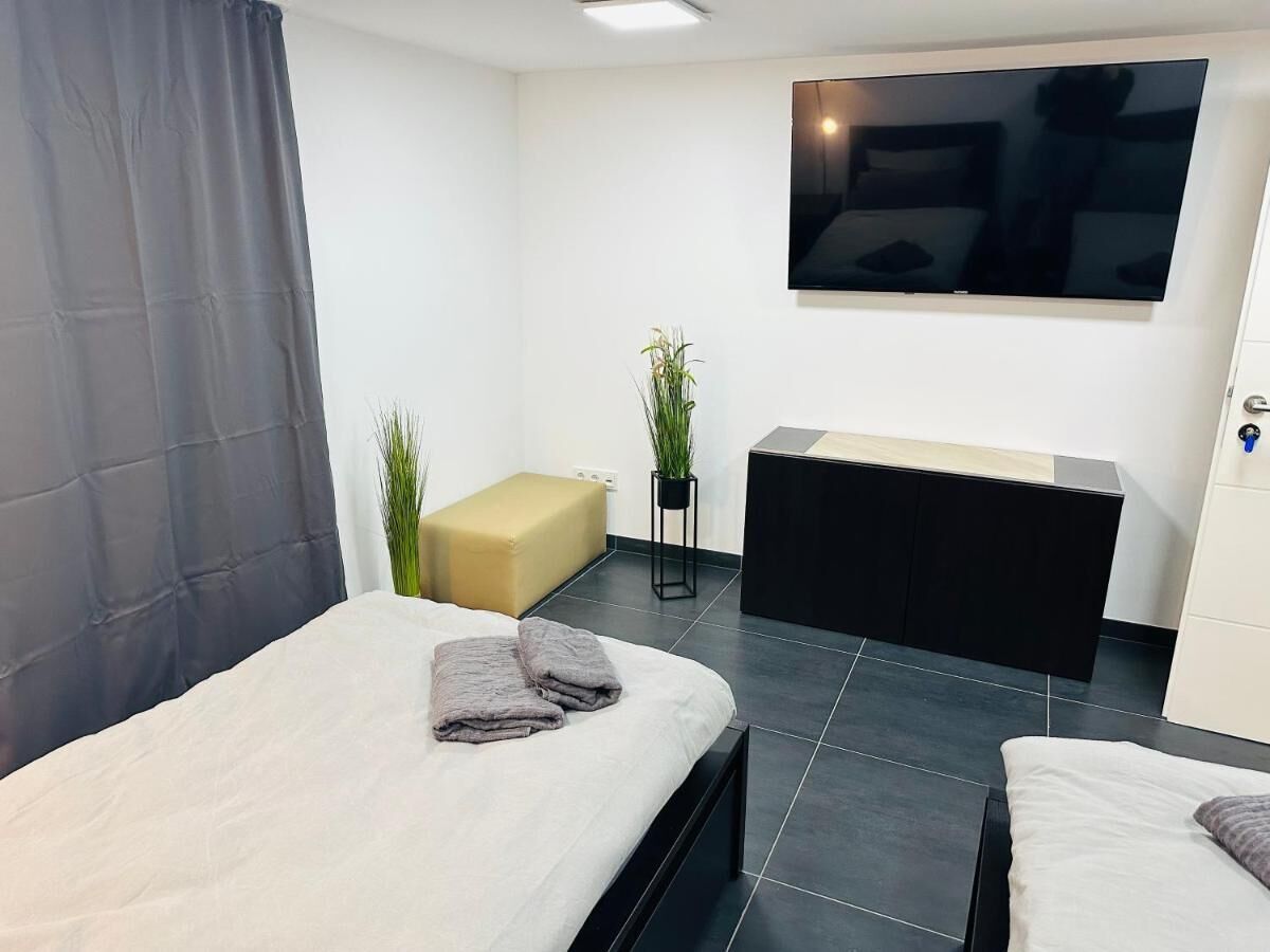 Een moderne hotelkamer met twee bedden, een bank, een televisie en een kleine plant.