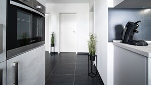 A modern kitchen with a built-in oven, a coffee machine, and two potted plants. - Blauer Stein - Echo bl7a-haus (Pulheim)