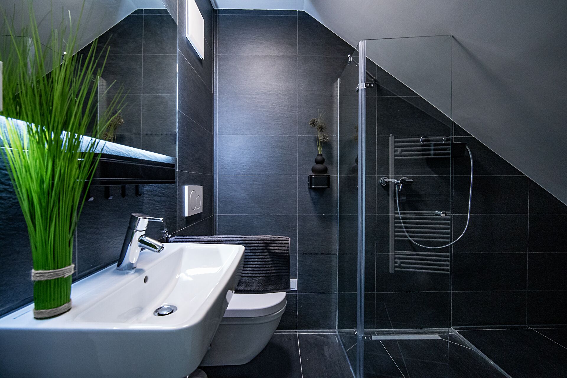 Ein modernes Badezimmer mit weißem Waschbecken, WC und Dusche.