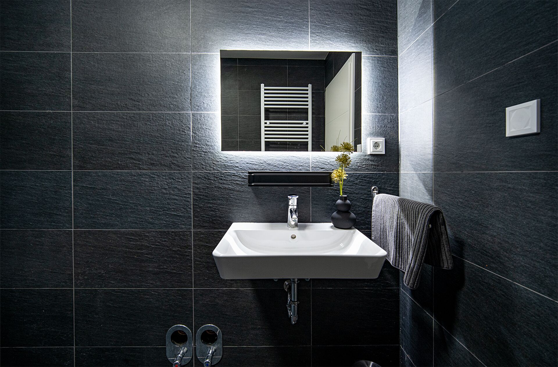 A bathroom with a white sink, a mirror, and a towel rack.