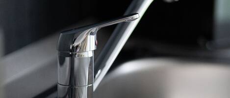 A modern kitchen sink with a sleek faucet and a stainless steel basin.