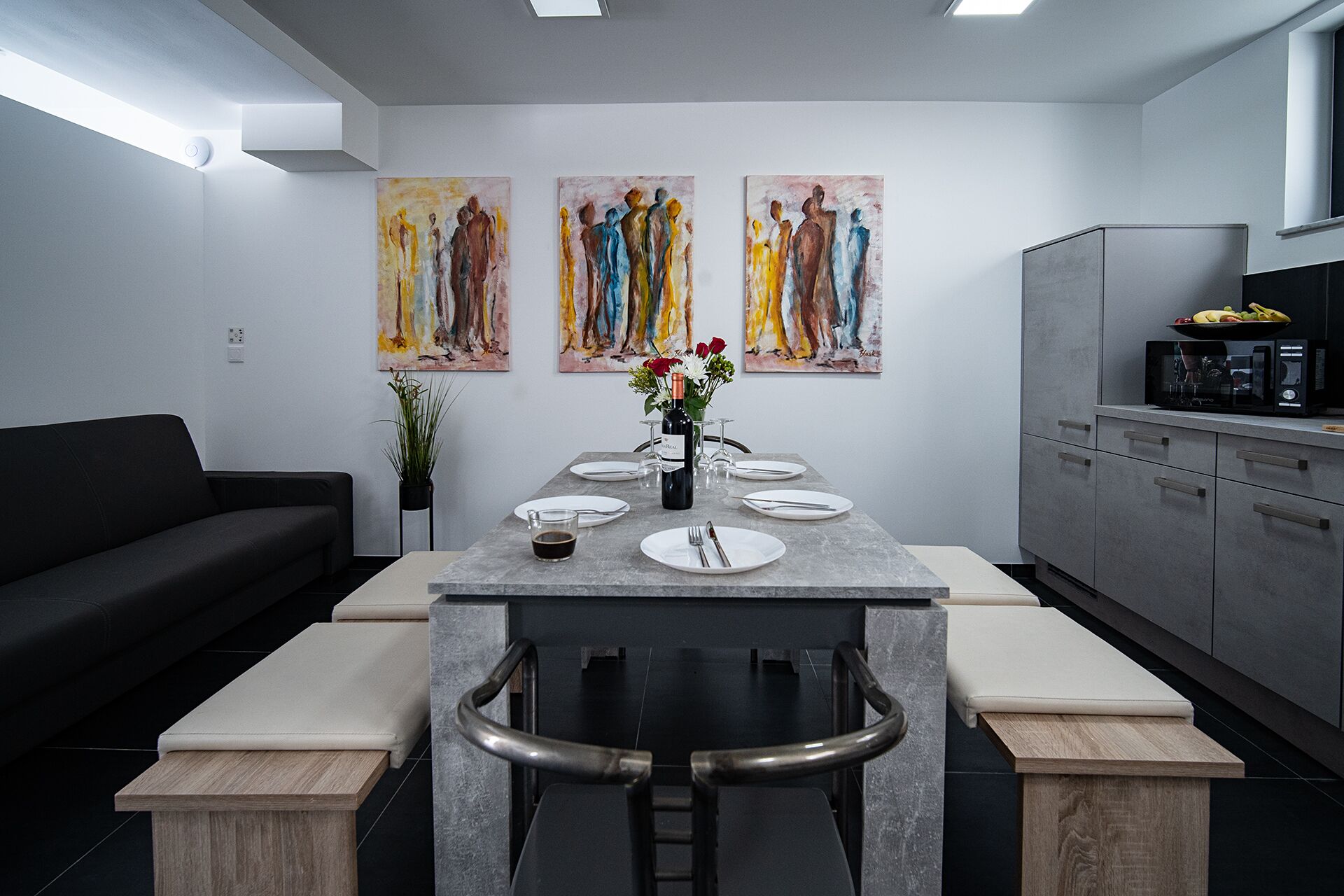 Una cucina moderna con zona pranzo, che include un tavolo lungo, sgabelli da bar e opere d'arte alle pareti.