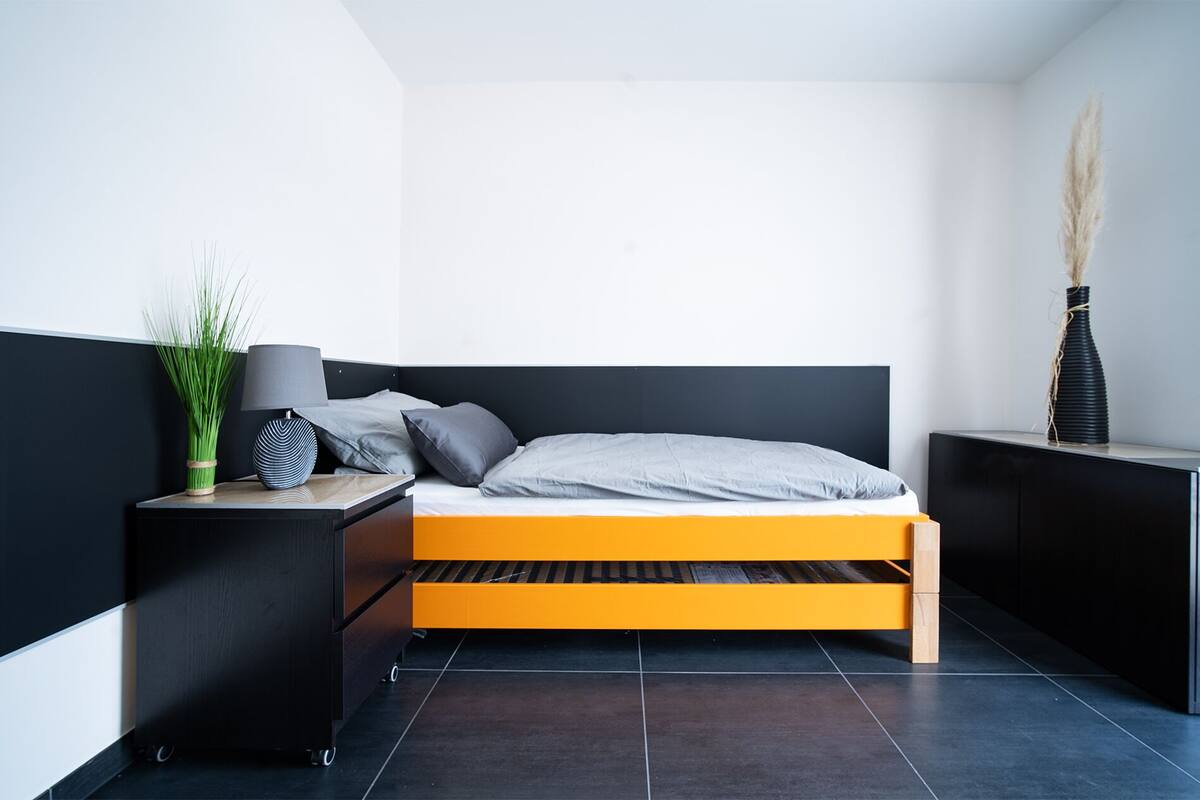 Een moderne slaapkamer met een bed, nachtkastje en een klein tafeltje met een lamp.
