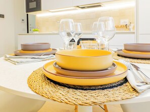 A dining table set with yellow and brown plates, clear glasses, and silverware. - Riva Real Estate - Lake Central Suite (Lecco)