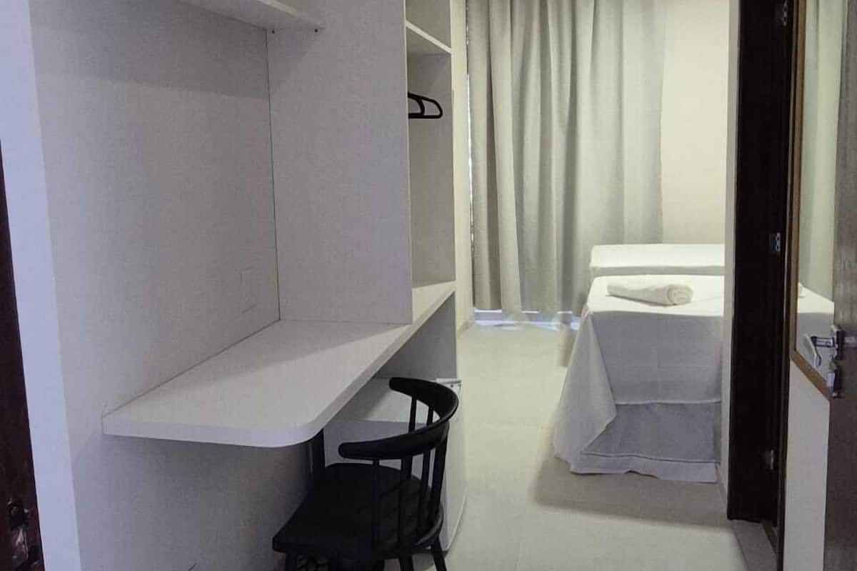 A compact hotel room with a bed, a desk, a chair, and a wardrobe.