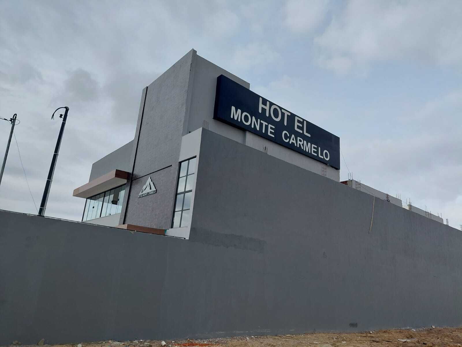 Ein modernes Hotel namens "Hotel Monte Carmelo" mit einer gut sichtbaren Schrifttafel.