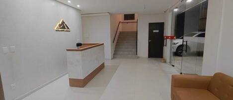 Ein modernes Interieur mit einer Rezeption, einer Treppe und einer Glastür zum Außenbereich.