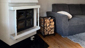 Una sala de estar moderna con chimenea blanca, un sofá gris y una ventana con cortinas estampadas.