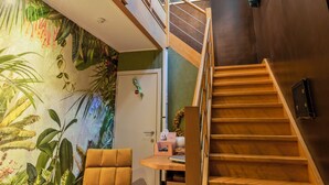 A modern interior with a wooden staircase, a vibrant mural, and a unique light fixture. - Hotel Brasserie de Klok (Zutendaal)