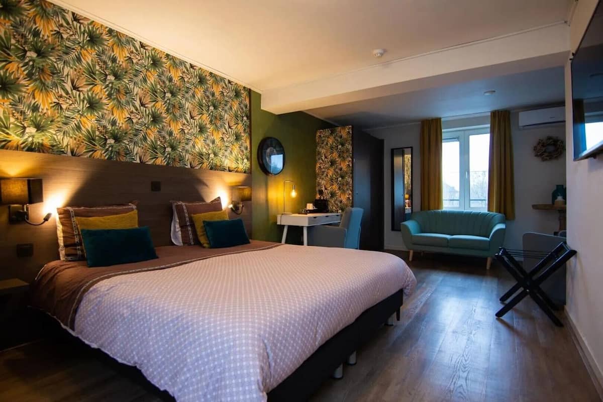 Une chambre d’hôtel avec un grand lit, un bureau, une chaise et un canapé.