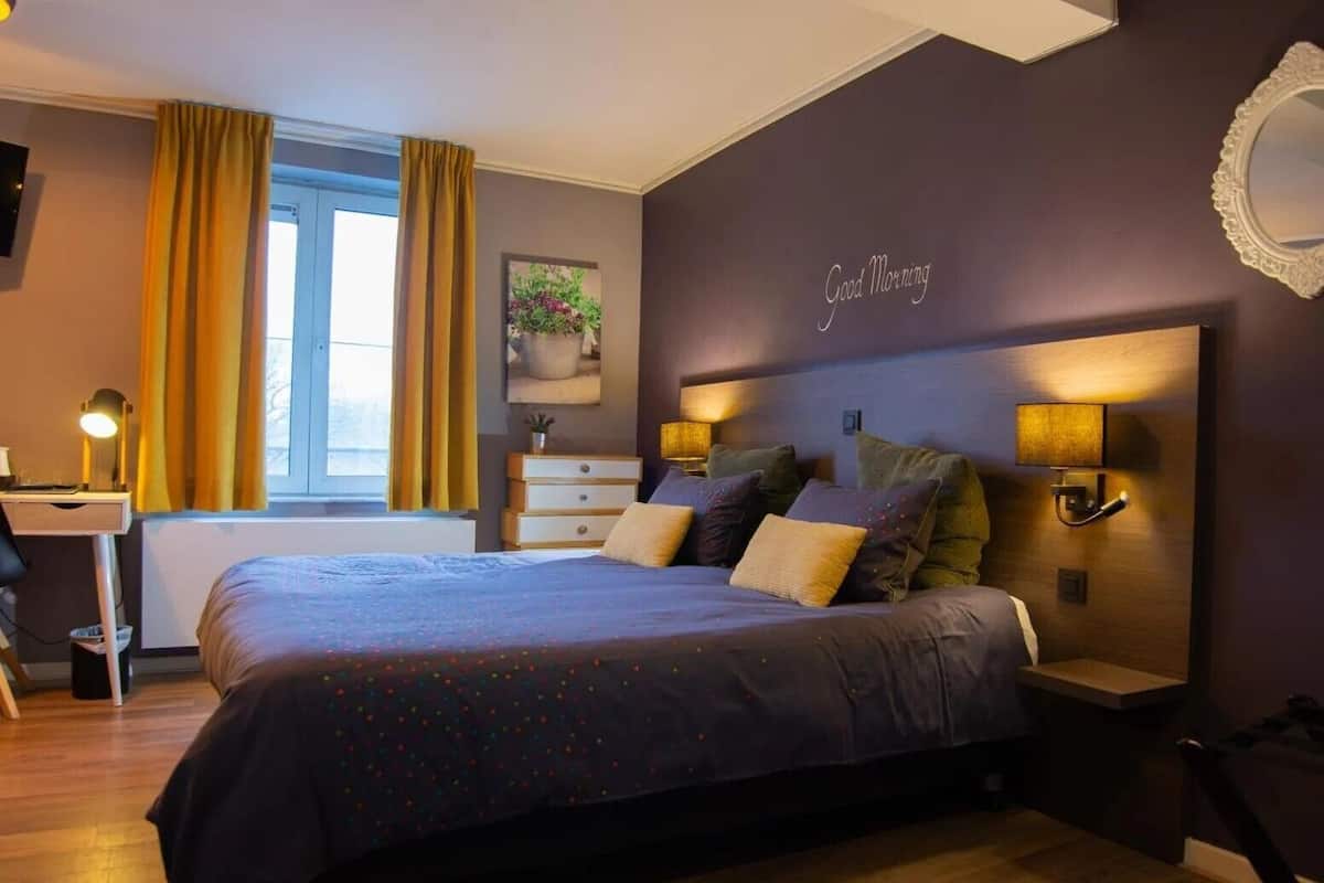 Une chambre moderne avec un grand lit, des lampes de chevet, un bureau et une fenêtre avec des rideaux.