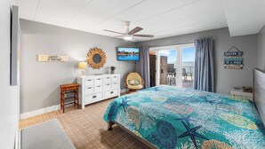 Quarto com cama, ventilador de teto, televisão e vista para o exterior.