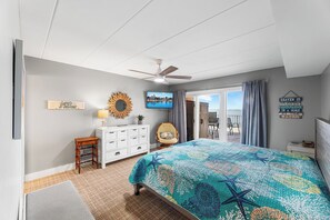 A bedroom with a bed, ceiling fan, TV, and a view of the outdoors. - Ponte Vista 206 – Waterfront Comfort & Sunset Views (Ocean City)