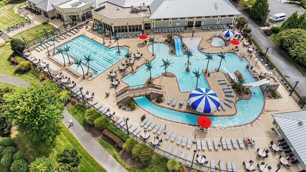 Um resort com várias piscinas, espreguiçadeiras e uma área coberta com guarda-sóis.