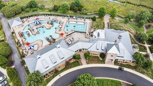 Vista aérea de um resort com piscina, áreas de descanso e um jardim bem cuidado.