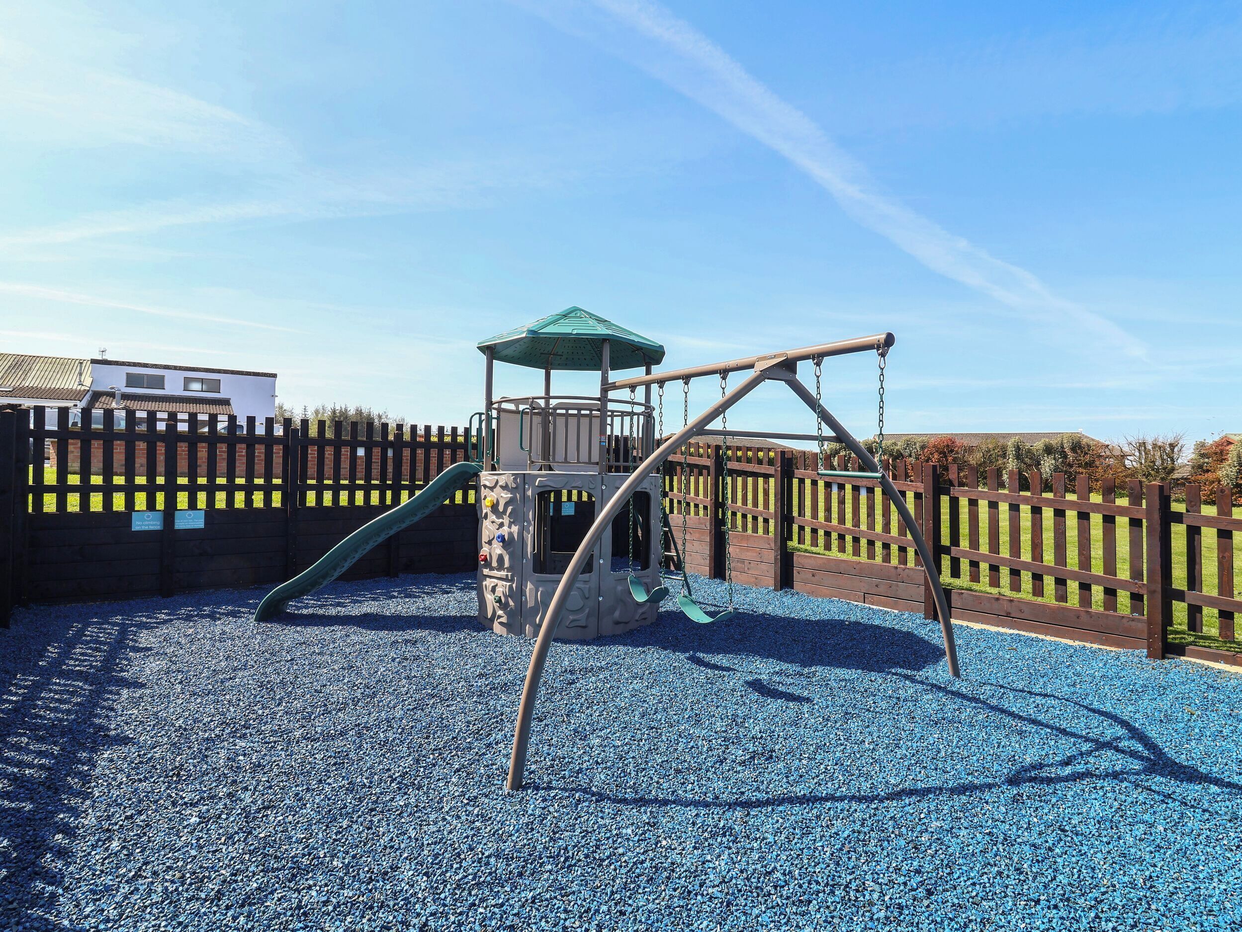 A playground with a swing set, climbing structure, and a fenced area.