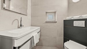 A modern bathroom with a white sink, a mirror, a small window, and a toilet. - Holiday Apartment Toronda (Vrvari-Poreč)