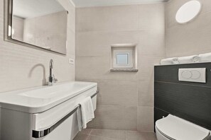 A modern bathroom with a white sink, a mirror, a small window, and a toilet. - Holiday Apartment Toronda (Vrvari-Poreč)
