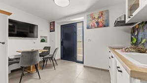 A modern kitchen with a built-in oven, a dining area with a wooden table and grey chairs, and a blue door leading to an outdoor area. - Holiday Apartment Toronda (Vrvari-Poreč)