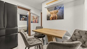 Et moderne køkken med et sort køleskab, et træspisebord og grå polstrede stole.