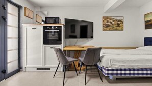 A compact room with a bed, a desk with a computer, a microwave, and a refrigerator. - Holiday Apartment Vanga (Vrvari-Poreč)