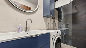 A modern bathroom with a built-in washing machine, a large mirror, and a shower area. - Holiday Apartment Vanga (Vrvari-Poreč)