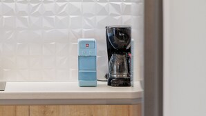 Una cocina con armarios de madera, una encimera blanca y una cafetera.
