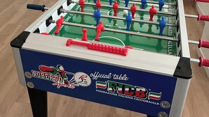 A foosball table with a blue and red player design, located in a room with a wooden floor, a small table, and a chair in the background. - B&B Malnati 3 Urban Living Milanosansiro (Milan)