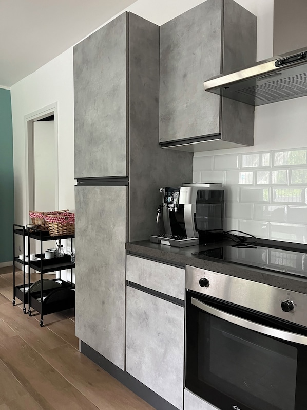 A modern kitchen with grey cabinetry, a built-in oven, and a coffee machine.