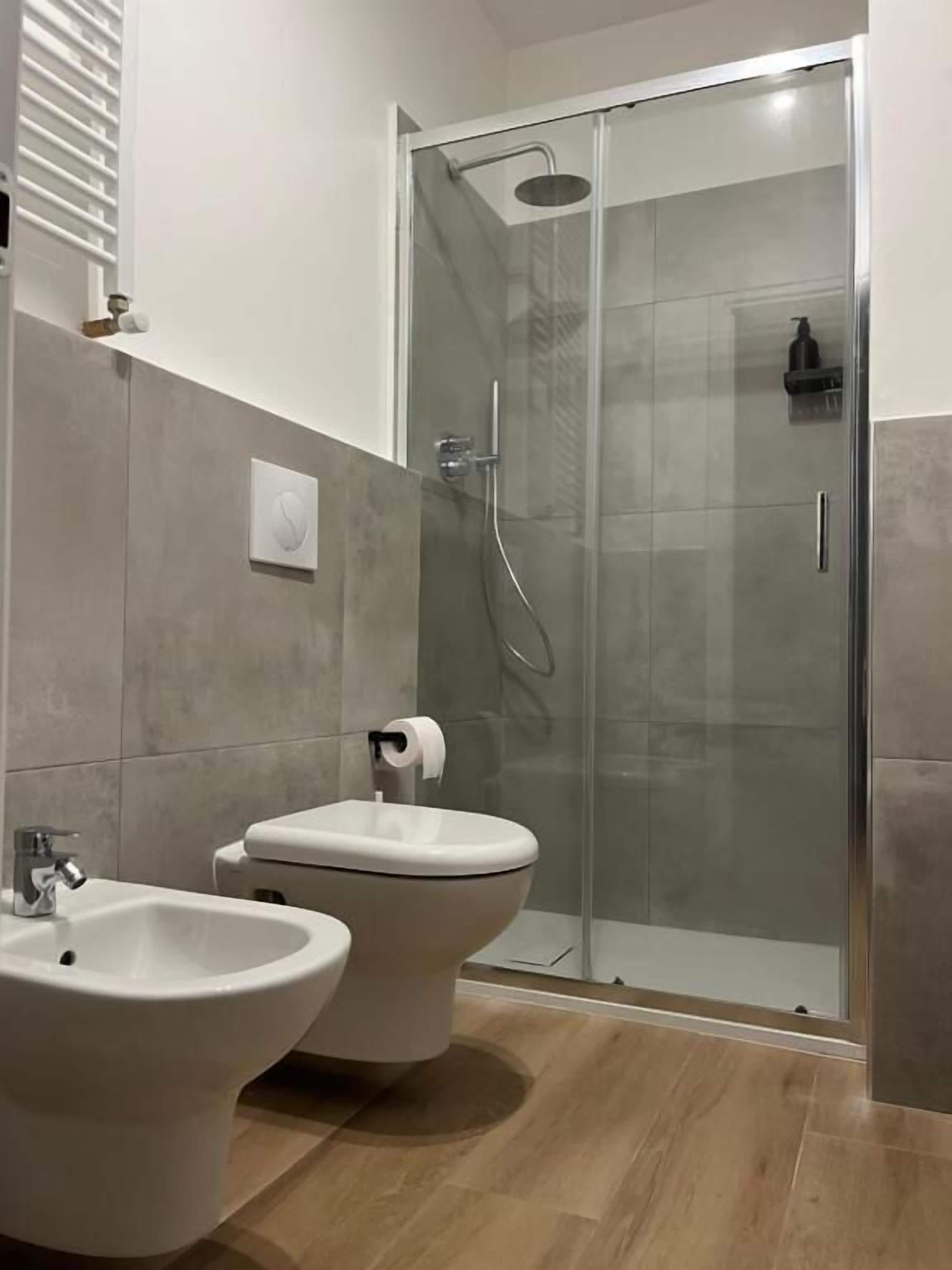 Ein modernes Badezimmer mit einer gläsernen Dusche, zwei Waschbecken und einer Toilette.